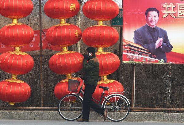 A man walks past a billboard featuring a photo of Chinese leader Xi Jinping beside lantern decorations for the Chinese Lunar New Year in Baoding, China on Feb. 24, 2015. (GREG BAKER/AFP via Getty Images)