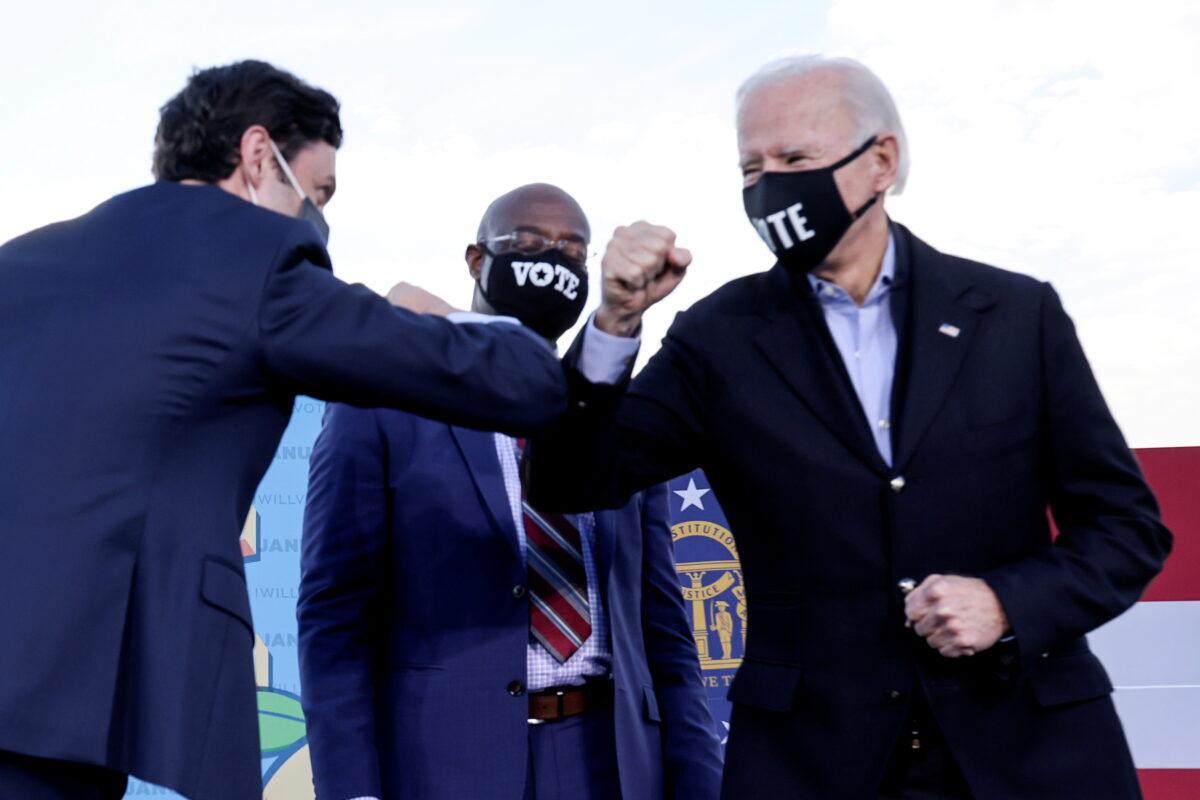 Then-presidential nominee Joe Biden elbow bumps Democratic Georgia Senate candidate Jon Ossoff, as fellow candidate Raphael Warnock looks on ahead of their Jan. 5 run-off elections, during a campaign rally in Atlanta, Ga., on Jan. 4, 2021. (Jonathan Ernst/Reuters)