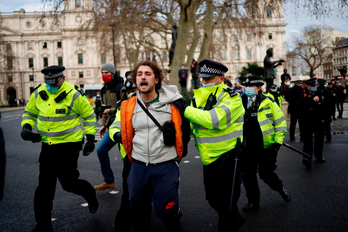 Police officers arrest a protester during an anti-CCP virus lockdown demonstration outside the Houses of Parliament in Westminster, central London on Jan. 6, 2021. (Tolga Akmen / AFP via Getty Images)