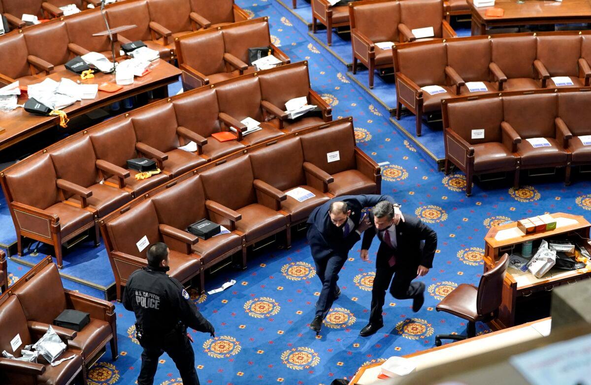 Members of congress run for cover as protesters try to enter the House Chamber during a joint session of Congress in Washington on Jan. 6, 2021. (Drew Angerer/Getty Images)