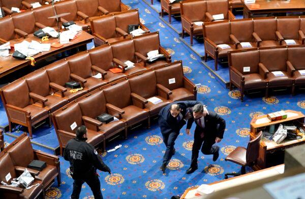 Members of congress run for cover as a group of protesters try to enter the House Chamber during a joint session of Congress in Washington on Jan. 6, 2021. (Drew Angerer/Getty Images)