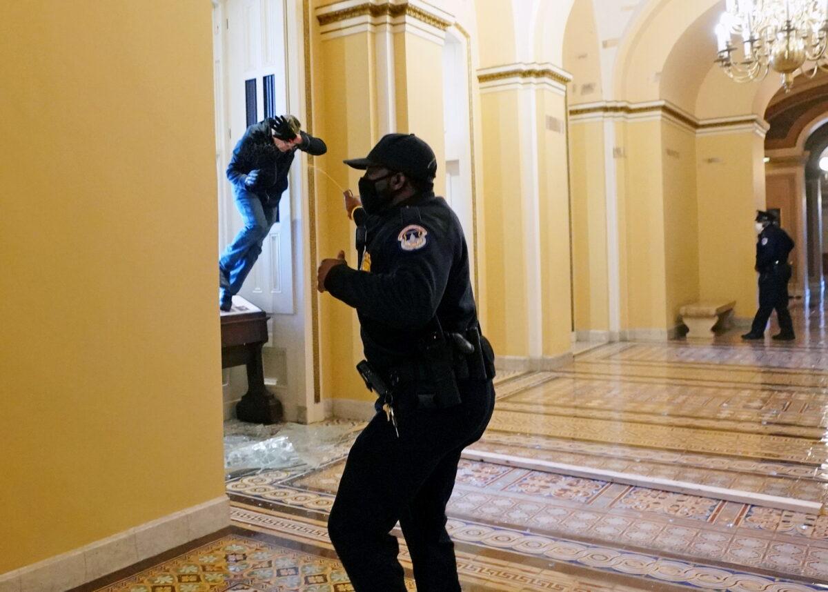  A U.S. Capitol police officer shoots pepper spray at a protestor attempting to enter the Capitol building during a joint session of Congress in Washington on Jan. 6, 2021. (Kevin Dietsch/Pool via Reuters)