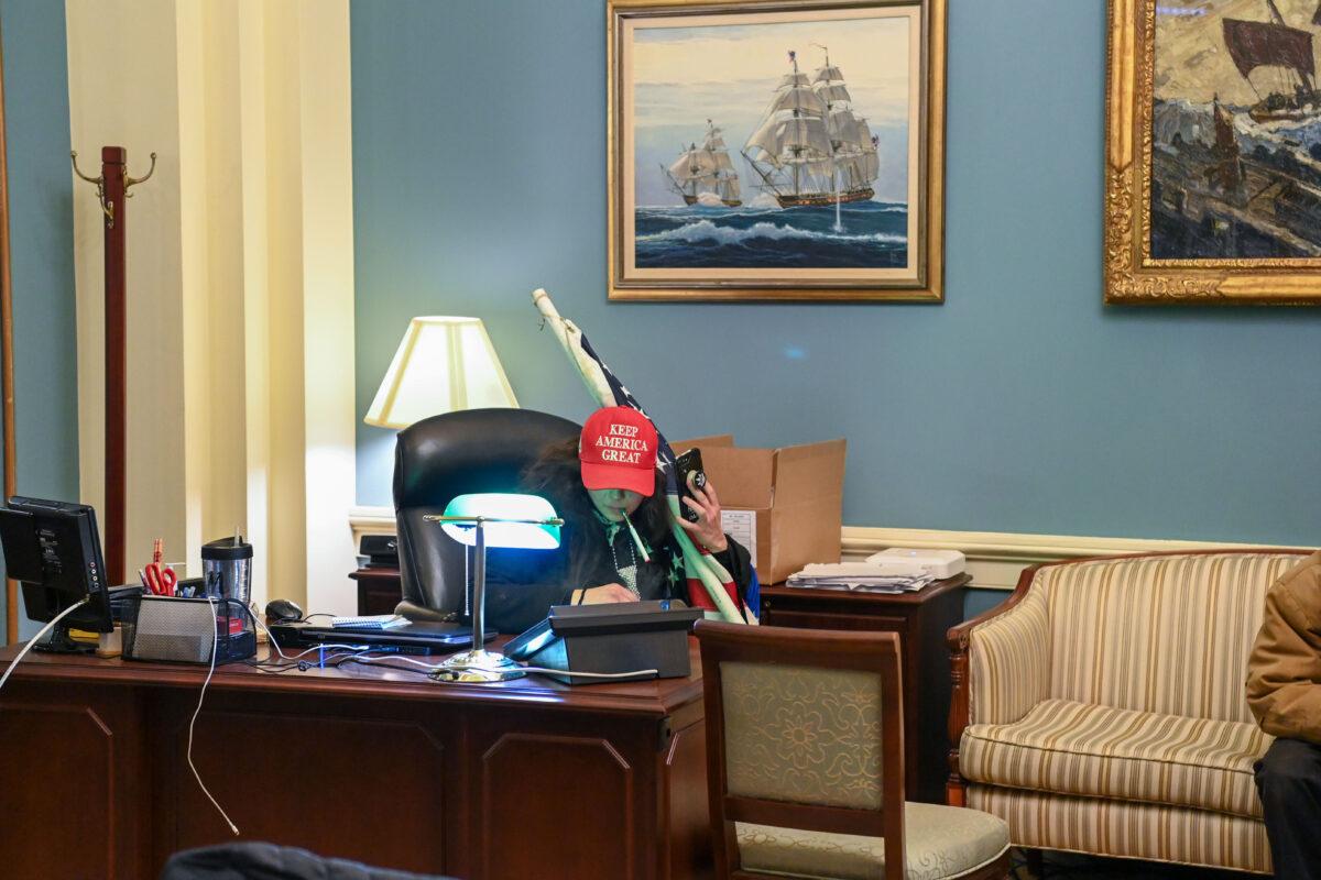 A protester wearing a 'Keep America Great' hat sits at a desk after invading the Capitol building in Washington, on Jan. 6, 2021. (Saul Loeb/AFP via Getty Images)
