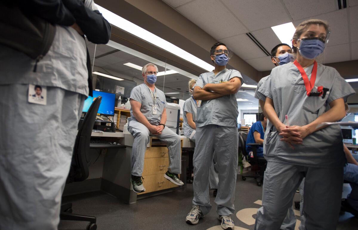 Dr. Del Dorscheid, centre, takes part in board rounds in the COVID-19 intensive care unit at St. Paul's hospital in downtown Vancouver, Canada, on April 21, 2020. (Jonathan Hayward/The Canadian Press)
