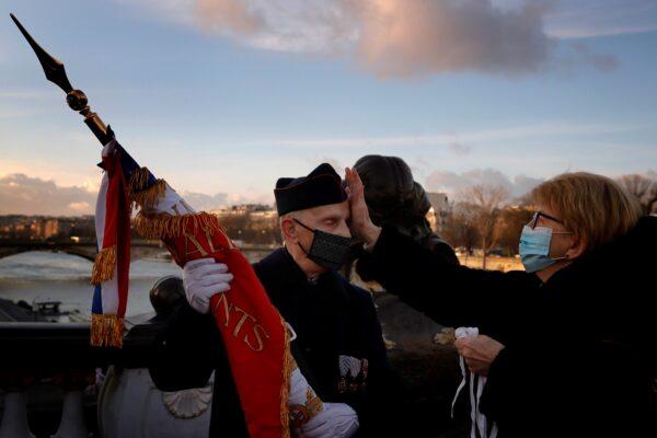 Solange adjusts the cap of her husband Gilbert, a French veteran before a ceremony held on the Alexandre III bridge in central Paris on Jan. 7, 2021. (Christophe Ena/AP Photo)