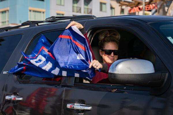 A woman in a car waves a Trump 2020 flag at a Stop The Steal Rally, in Huntington Beach, Calif., on Jan 6, 2021. (John Fredricks/The Epoch Times)