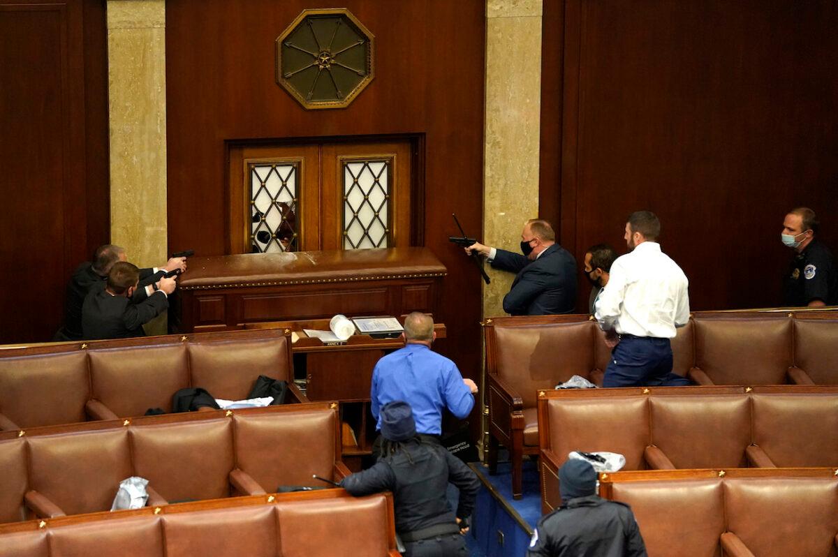 Law enforcement officers point their guns at a door that was vandalized in the House Chamber during a joint session of Congress in Washington on Jan. 6, 2021. (Drew Angerer/Getty Images)