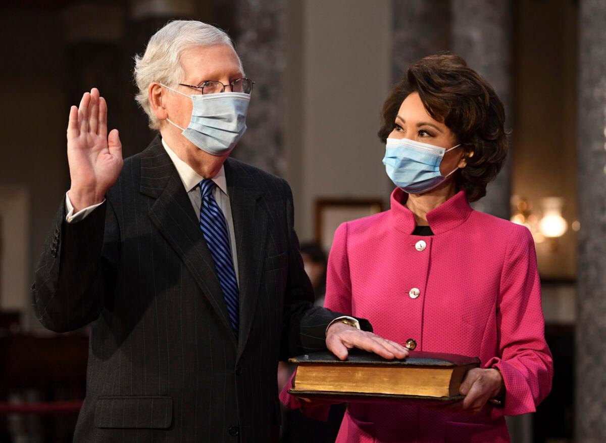 Sen. Mitch McConnell (R-Ky.) participates in a mock swearing-in as his wife, Transportation Secretary Elaine Chao, holds a Bible, in the Old Senate Chamber at the Capitol in Washington on Jan. 3, 2021. (Kevin Dietsch/Pool via AP)