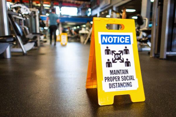 A sign encourages members to maintain proper social distancing inside World Gym in Tujunga, Calif., on Jan. 5, 2021. (John Fredricks/The Epoch Times)