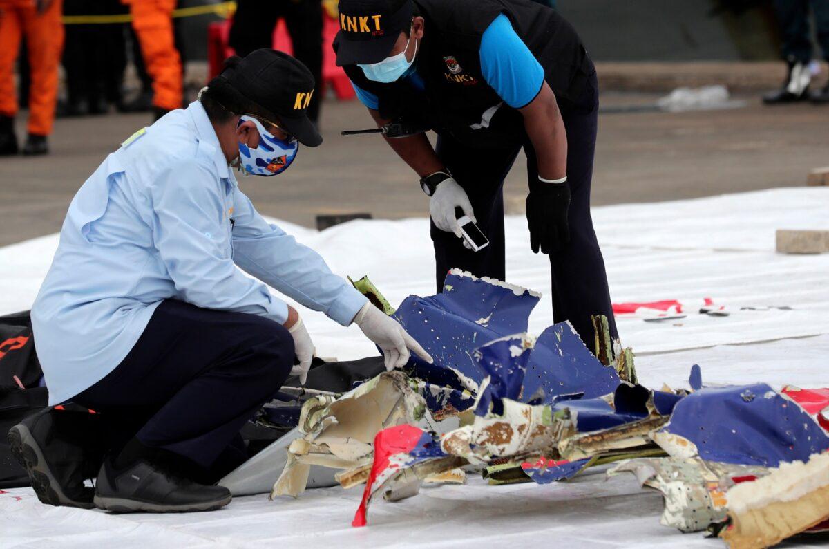 Investigator of Indonesian National Transportation Safety Committee inspect parts of Sriwijaya Air Flight 182 that crashed in the waters off Java Island, at Tanjung Priok Port in Jakarta, Indonesia, on Jan. 10, 2021. (Tatan Syuflana/AP Photo)