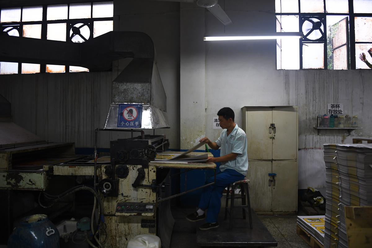 A worker operating machinery in a printing factory in Nanjie Village, in China's central Henan Province, on Sept. 26, 2017. (GREG BAKER/AFP via Getty Images)