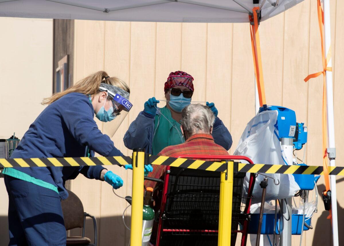 Health care workers attending to a patient as St. Mary Medical Center resort to using triage tents outside to handle the overflow at its 200 bed hospital during the outbreak of the CCP virus in Apple Valley, Calif., on Jan. 12, 2021. (Mike Blake/Reuters)