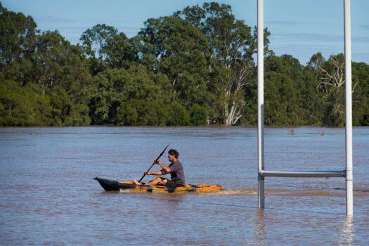 A resident uses a kayak to paddle past goalposts, partially submerged under floodwaters caused by Cyclone Debbie, to rescue a stranded cow on his property in North MacLean, Brisbane on April 1, 2017. (Photo by PATRICK HAMILTON/AFP via Getty Images)
