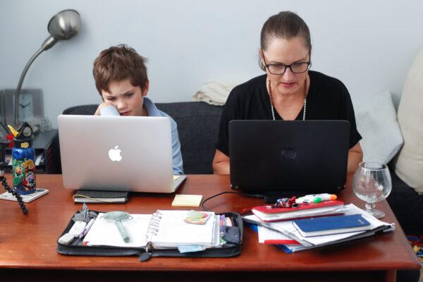 Phoenix Crawford does school work on a laptop while his mum Donna Eddy replies to client emails in Sydney on April 9, 2020, Australia. (Brendon Thorne/Getty Images)