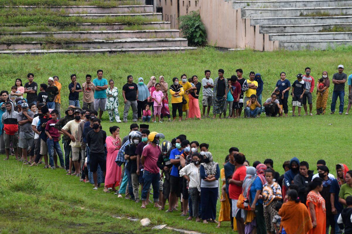 People stand in line for aid assistance at the Manakarra stadium following an earthquake in Mamuju, West Sulawesi province, Indonesia, on Jan. 17, 2021. (Sigid Kurniawan/Antara Foto via Reuters)