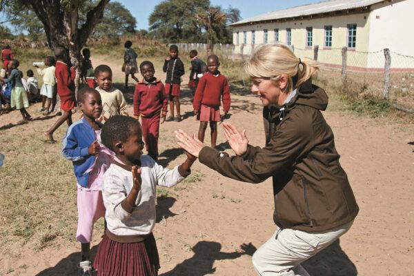 A member of an Overseas Adventure Travel tour group interacts with children in Zimbabwe. (Courtesy of the Grand Circle Corp.)