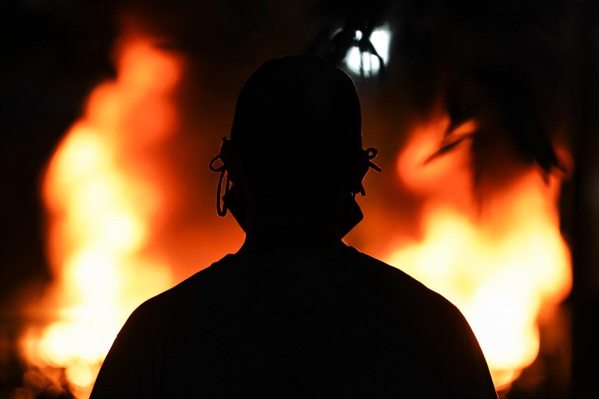 A man wearing a face mask is silhouetted in front of a burning police car in Atlanta, Ga., on May 29, 2020. (Elijah Nouvelage/Getty Images)