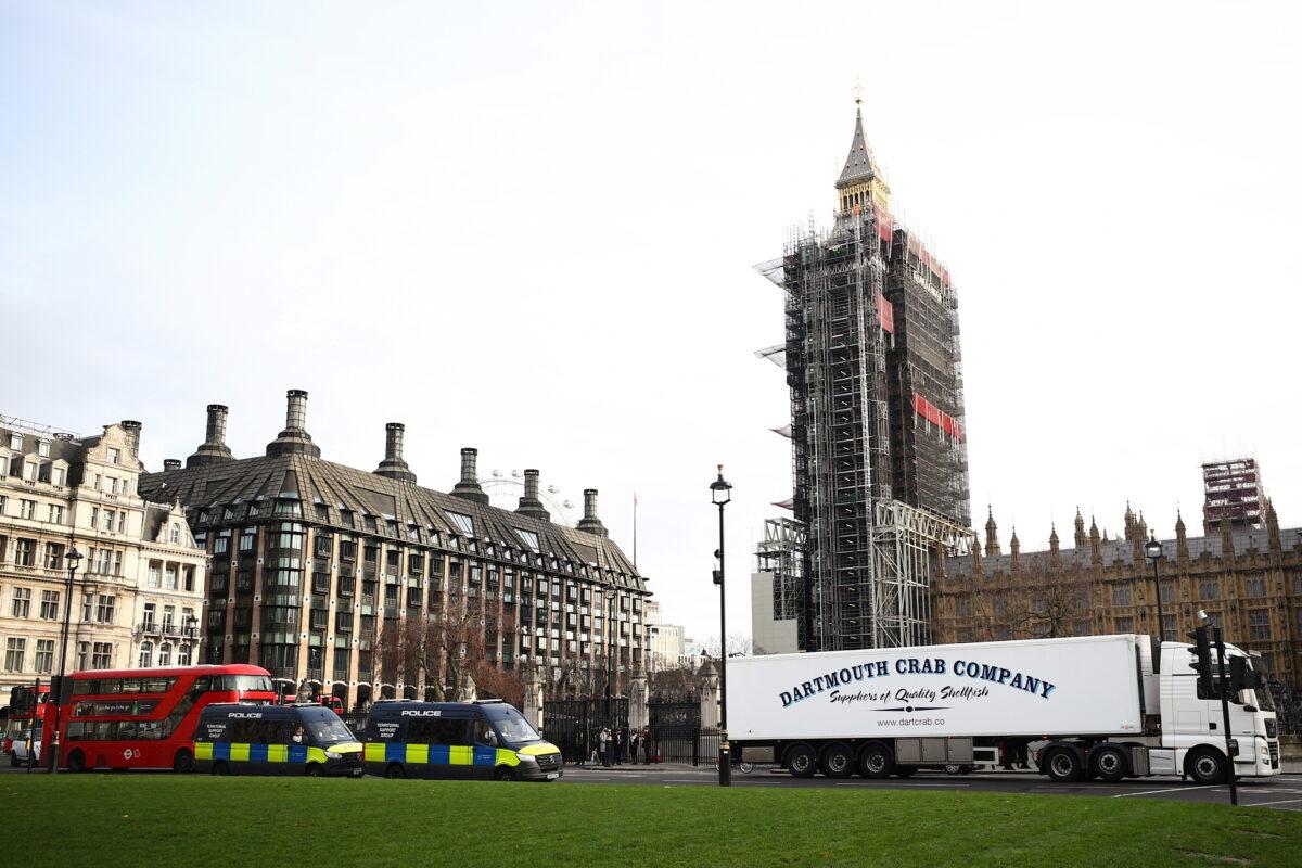 A lorry drives during a protest against post-Brexit bureaucracy that hinders exports to the European Union, as police officers in vans watch over the demonstration at the Parliament Square in London, on Jan. 18, 2021. (Hannah McKay/Reuters)