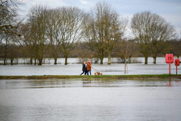 A woman walks along the path between the waterlogged flood plains and the River Great Ouse, in Godmanchester, Cambridgeshire. England, on Jan. 19, 2021. (Leon Neal/Getty Images)
