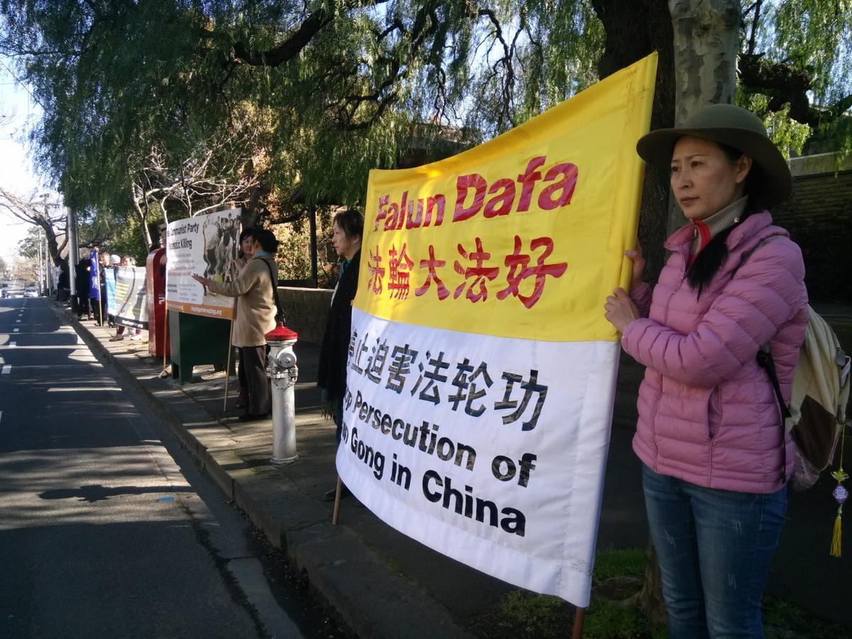 Angel holding the banner of “Stop Persecuting Falun Gong” opposite the main entrance of the Chinese Consulate in Toorak in Melbourne, Australia. (Courtesy of Angel)