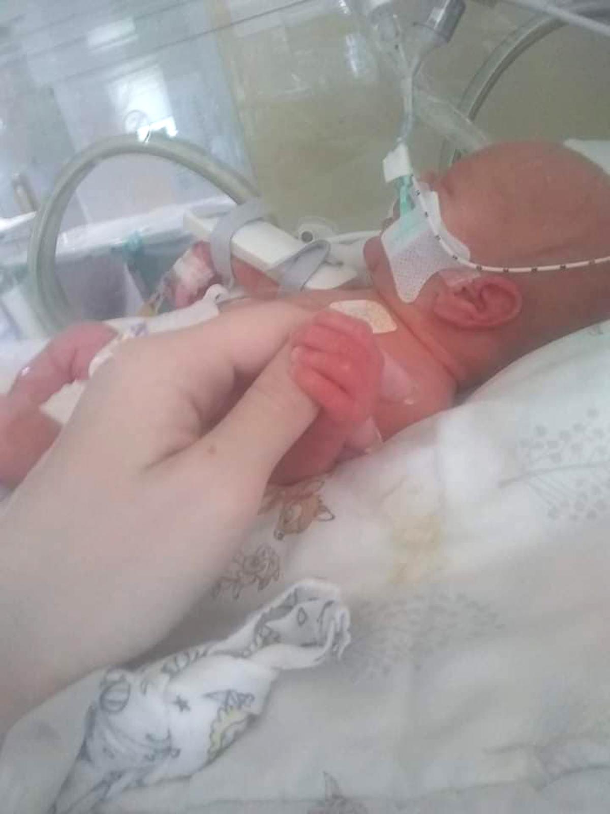 Sarah Milner holding baby Louis's hand in NICU after he was born 8 weeks early. (Caters News)