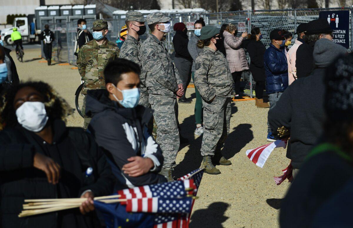 Members of the National Guard look on as people collect flags that decorated the National Mall in Washington on Jan. 21, 2021. (Brendan Smialowski/AFP via Getty Images)