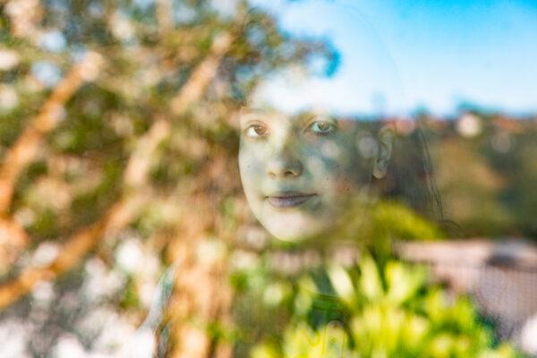 Sydney R. looks out a window at a home in Laguna Niguel, Calif., on Jan. 21, 2021. (John Fredricks/The Epoch Times)