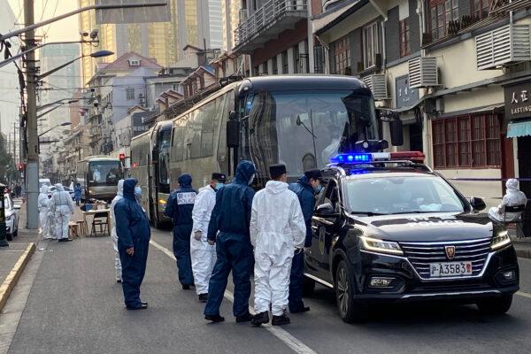 Police and workers stand next to buses in a neighbourhood where residents are forced to go to centralized quarantine centers in Huangpu district in Shanghai, China, on Jan. 21, 2021. (STF/AFP via Getty Images)