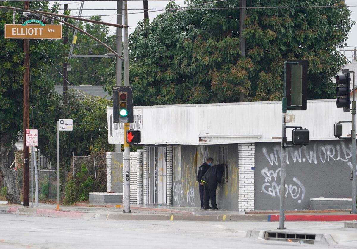 El Monte Police Chief David Reynoso, left, with another officer peeks inside the church's windows after an explosion in El Monte, Calif., Saturday, Jan. 23, 2021. (Damian Dovarganes/AP Photo)