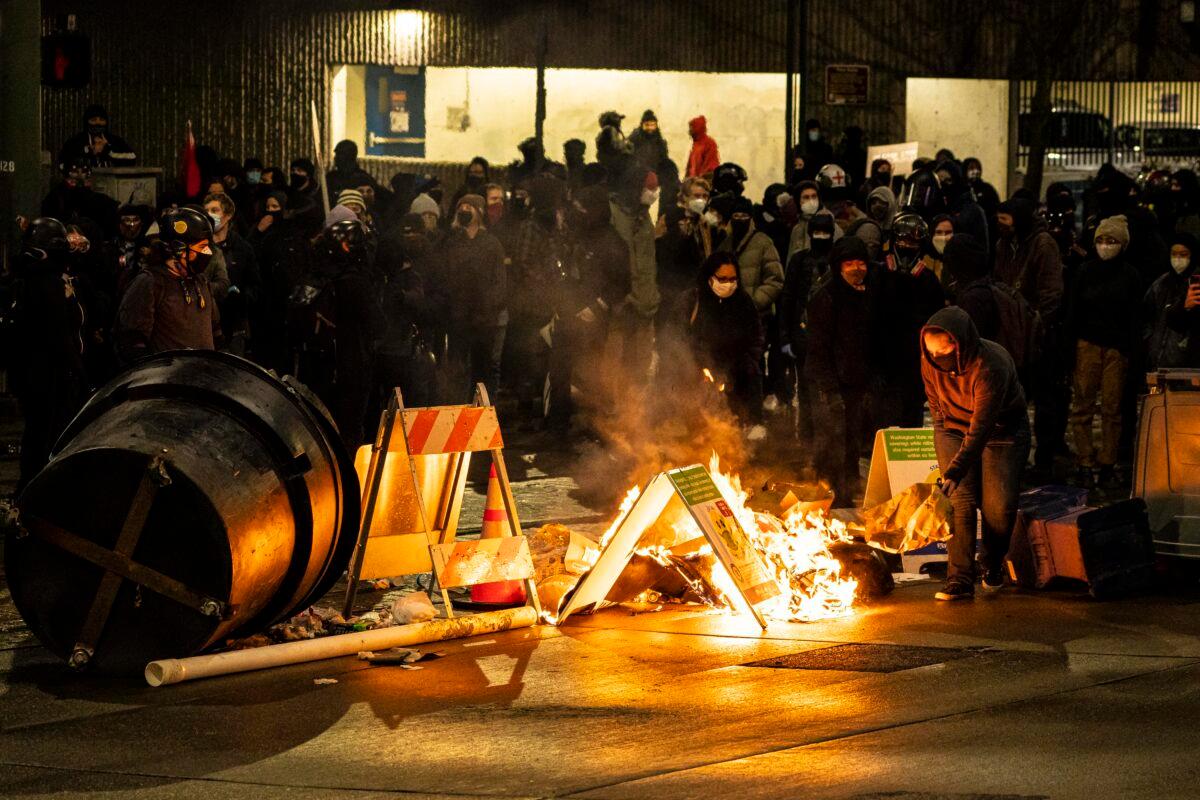 A demonstrator adds fuel to a burning barricade in an intersection in downtown Tacoma, Wash., on Jan. 24, 2021. (David Ryder/Getty Images)