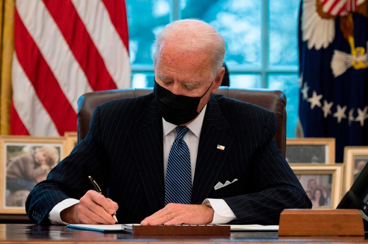 President Joe Biden signs an Executive Order reversing the Trump-era ban on transgender individuals serving in the military, in the Oval Office of the White House in Washington on Jan. 25, 2021. (Jim Watson/AFP via Getty Images)