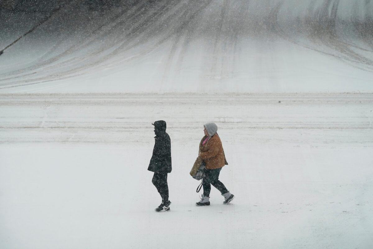 Pedestrians cross a snow covered street, in downtown Des Moines, Iowa, on Jan. 25, 2021. (Charlie Neibergall/AP Photo)