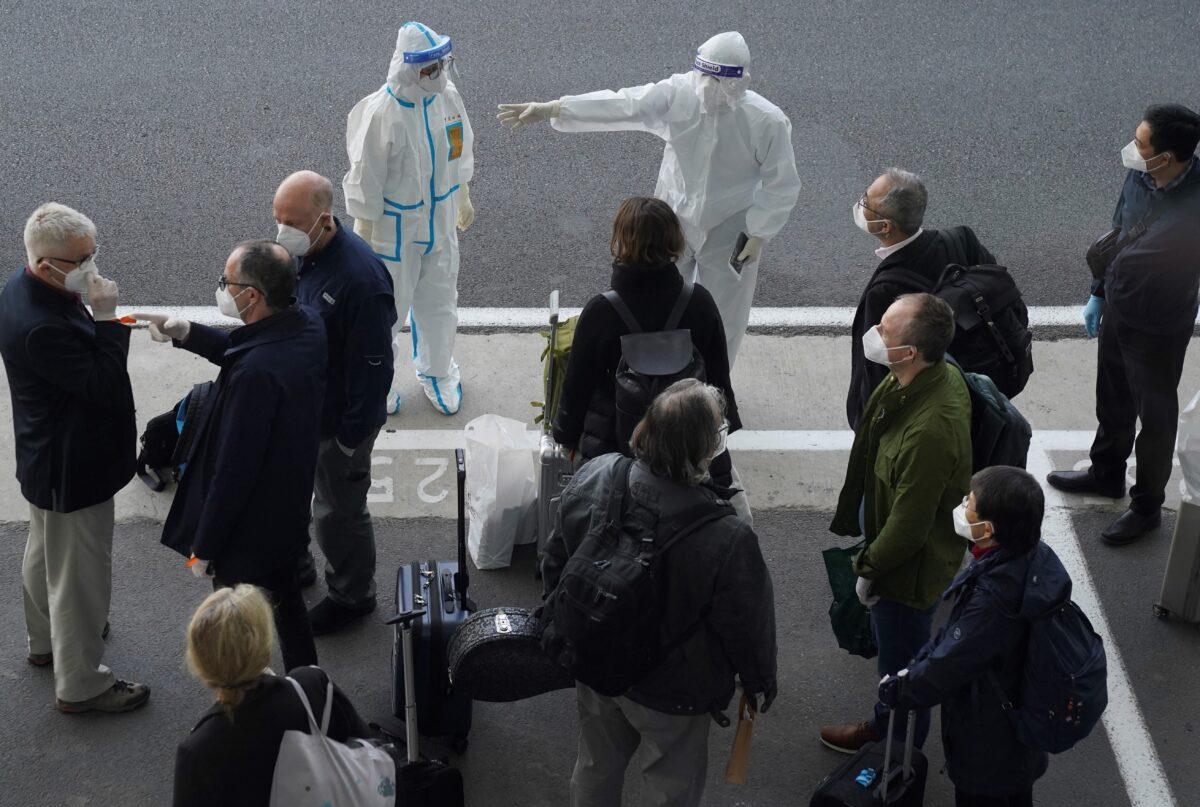 A worker in protective coverings directs members of the World Health Organization (WHO) team on their arrival at the airport in Wuhan in central China's Hubei province on Jan. 14, 2021. (Ng Han Guan/AP Photo)