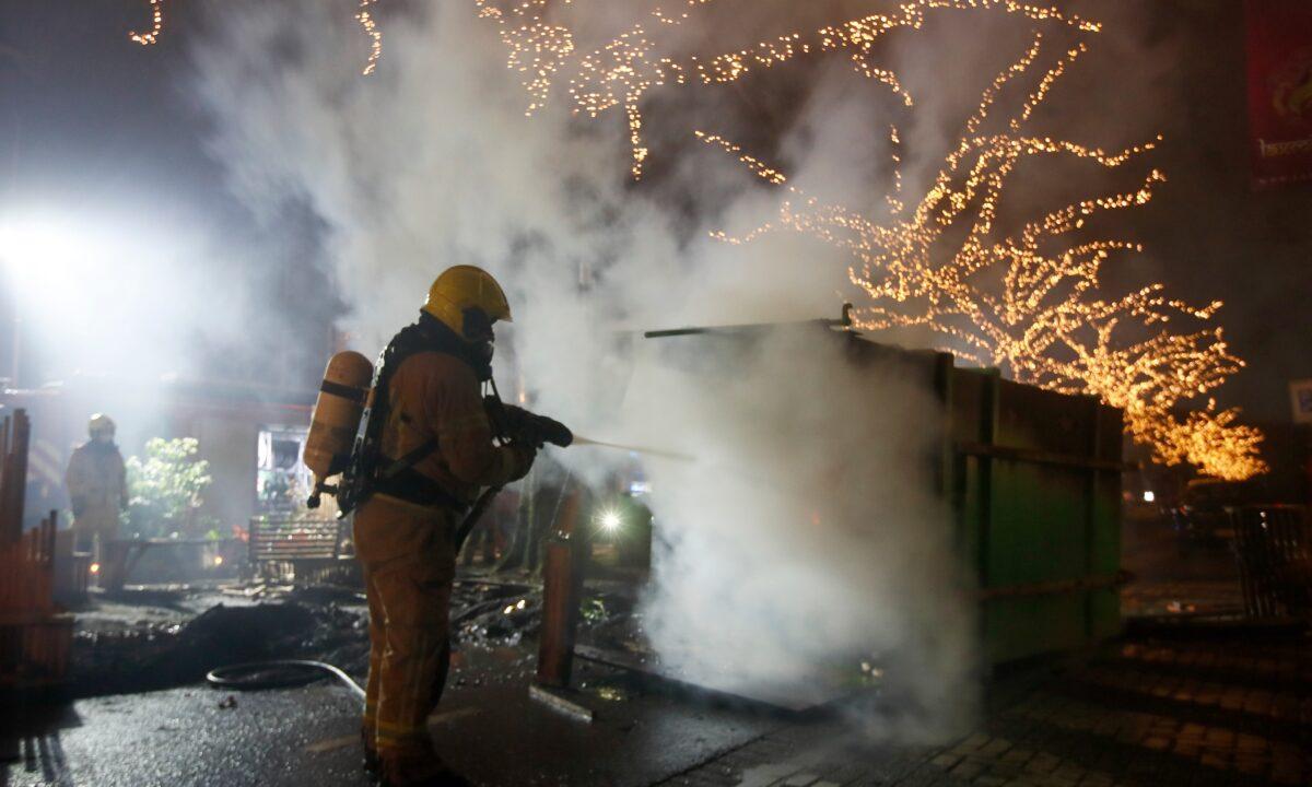 A firefighter extinguishes a container that was set alight during protests against a nation-wide curfew in Rotterdam, Netherlands, on Jan. 25, 2021. (Peter Dejong/AP Photo)