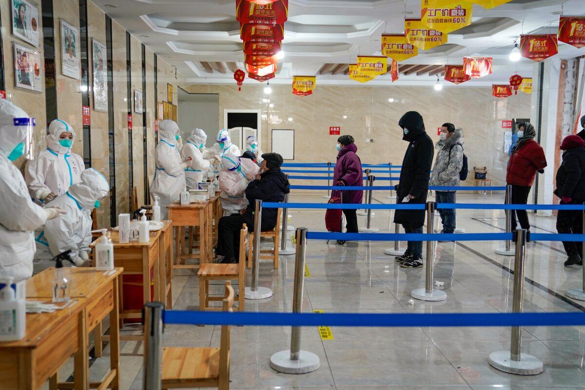 A medical worker takes a swab sample from a man as people queue to get tests for Covid-19 coronavirus at an office building in Harbin, in northeastern China's Heilongjiang Province on Jan. 14, 2021, after the province declared an "emergency state" as daily Covid-19 numbers climb. (STR/AFP via Getty Images)