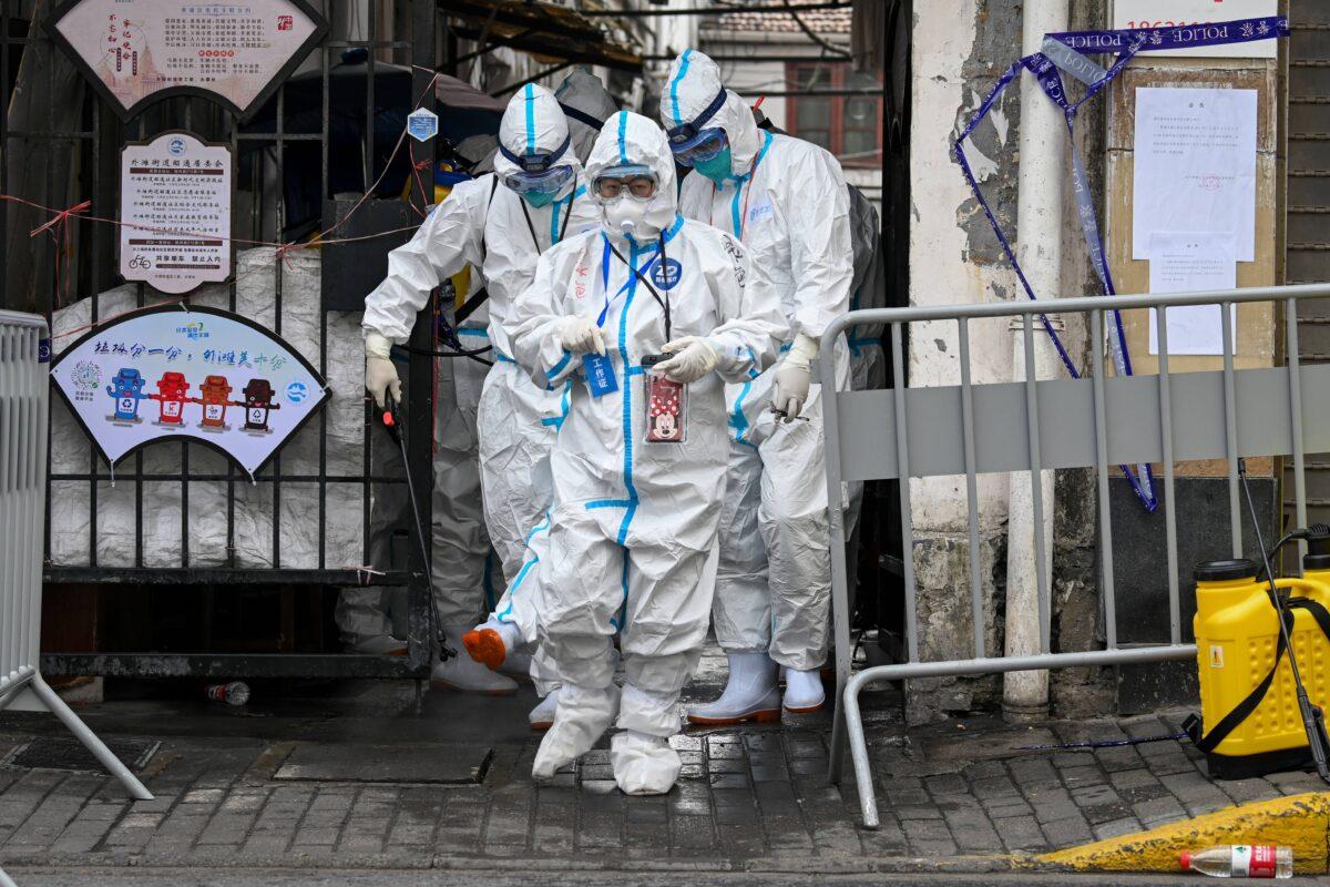 Health workers in protective gear walk out from a blocked-off area after spraying disinfectant in Shanghai's Huangpu district on Jan. 27, 2021. Residents were evacuated after a few cases of COVID-19 were detected in the neighborhood. (STR/AFP via Getty Images)