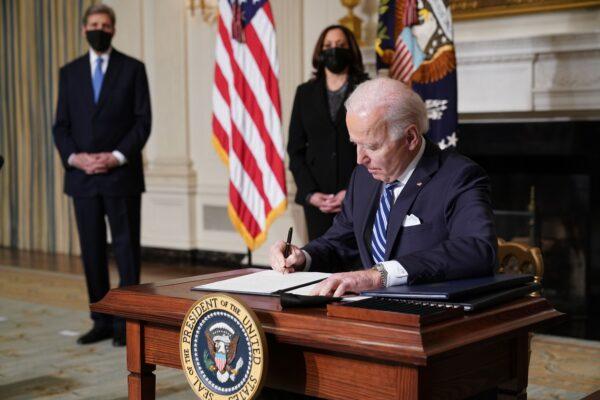 Vice President Kamala Harris (C) and special presidential envoy for climate John Kerry (L) watch as President Joe Biden signs executive orders related to climate change, including one directing a pause on new oil and natural gas leases on public land, on Jan. 27, 2021. (Mandel Ngan/AFP via Getty Images)