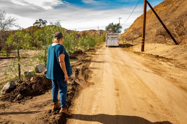 Susan Iwamoto watches a trailer leave Williams Canyon as part of a voluntary evacuation due to expected flooding in Orange County, Calif., on Jan. 28, 2021. (John Fredricks/The Epoch Times)