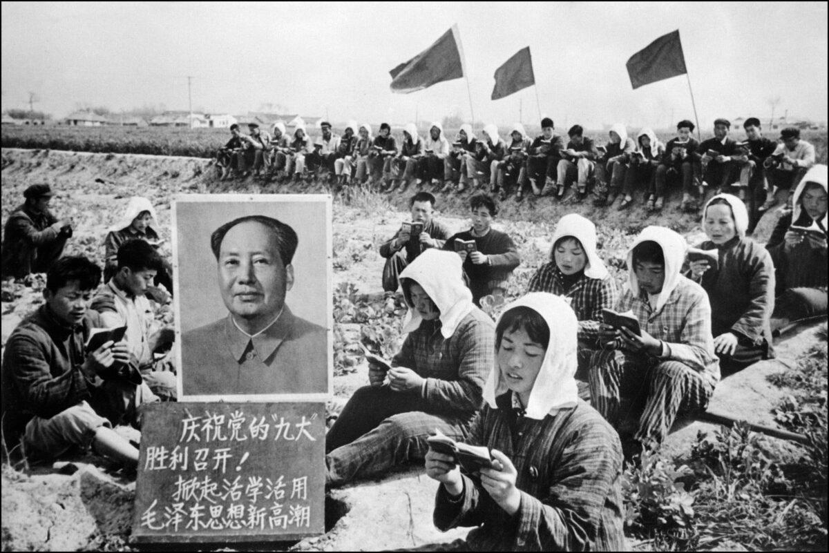 A picture released in 1969 by the Chinese official news agency shows workers gathered in a field around a huge portrait of Chinese Communist Party leader Mao Zedong. (Xinhua/AFP via Getty Images)