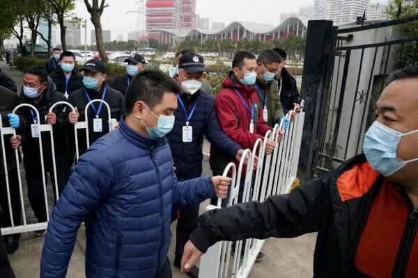 Security personnel move a barrier to clear the way for the World Health Organization team as they depart from the Wuhan Jinyintan Hospital after a field visit in Wuhan in central China's Hubei province on Jan. 30, 2021. (Ng Han Guan/AP)