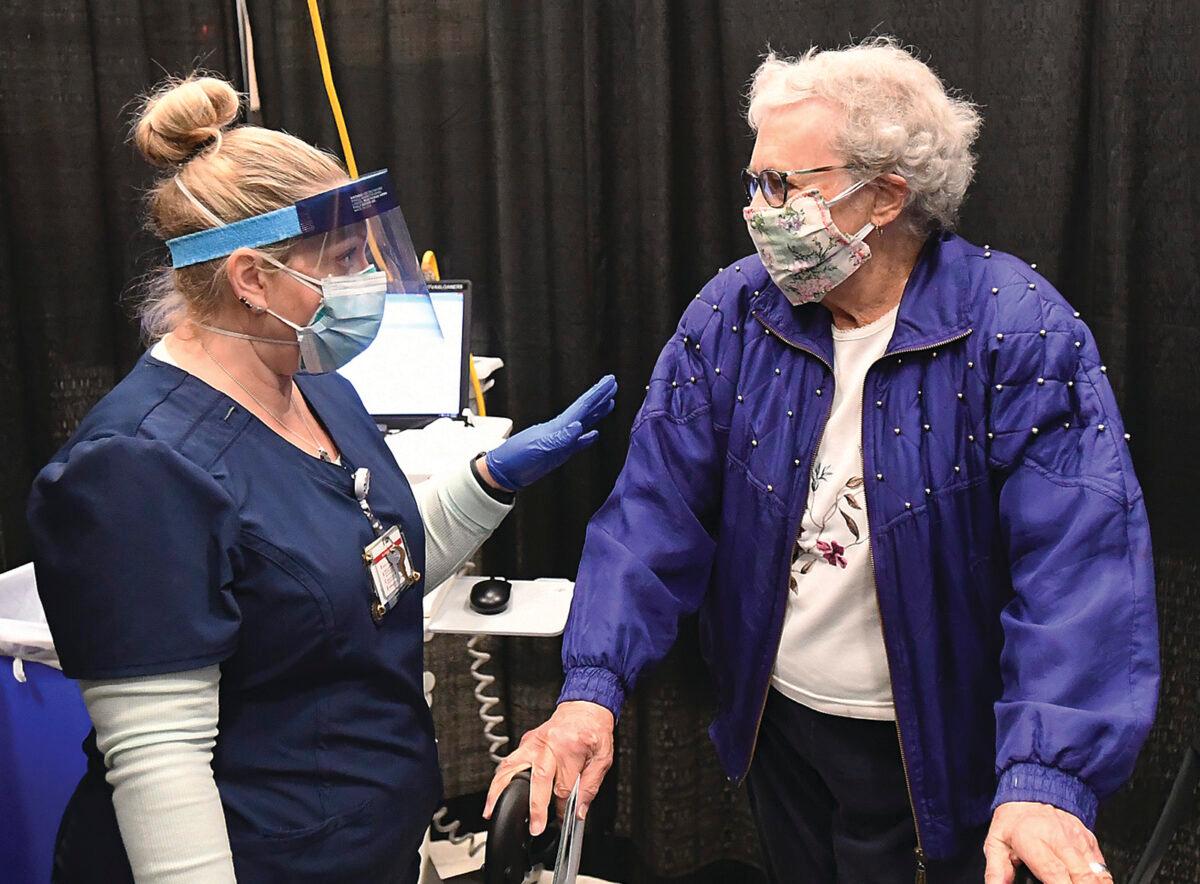 A nurse (L) answers questions after an elderly woman received a CCP virus vaccination inside Yuma Civic Center in Yuma, Ariz., on Jan. 28, 2021. (Randy Hoeft/The Yuma Sun via AP)