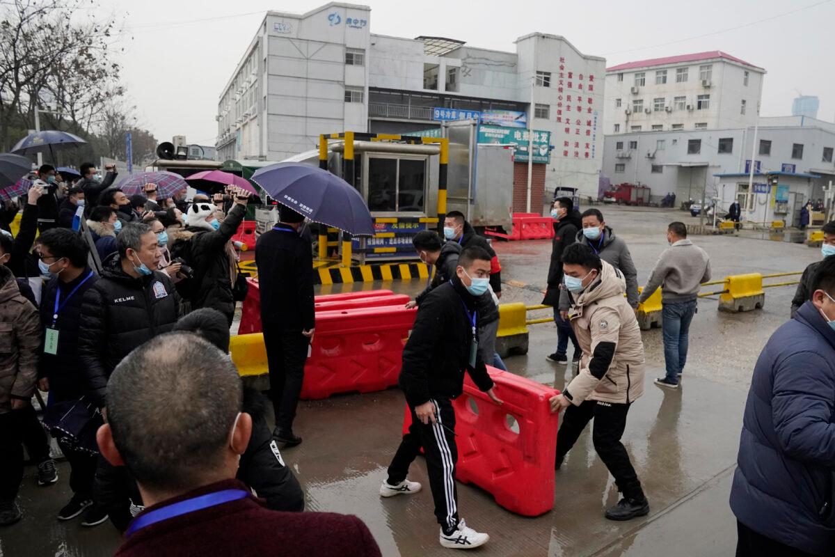 Security personnel use barriers to block the way after the World Health Organization team arrive at the Baishazhou wholesale market on the third day of field visit in Wuhan, China, on Jan. 31, 2021. (Ng Han Guan/AP Photo)