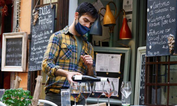 A staff member pours wine at a restaurant in Trastevere after the COVID-19 restrictions were eased in the Lazio region, Rome, Italy, on Feb. 1, 2021. (Guglielmo Mangiapane/Reuters)