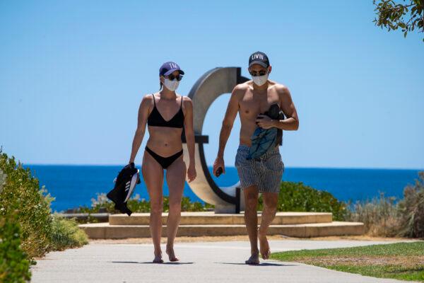 A young couple at Cottesloe Beach wearing mandatory face masks after an hour of recreational exercise is permitted in Perth, Australia on Feb. 1, 2021. (Matt Jelonek/Getty Images)
