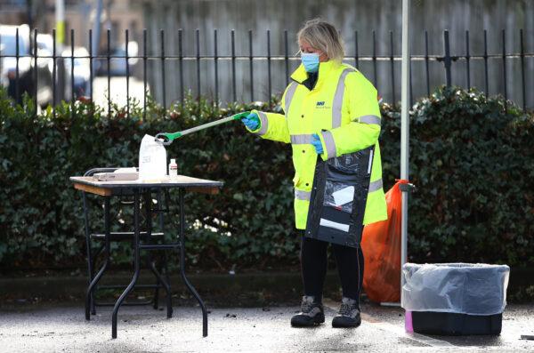 A woman cleans up after a CCP virus test at a temporary testing facility in West Ealing, London, on Feb. 2, 2021. (Hollie Adams/Getty Images)