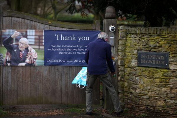 A person lays flowers at the gate to the residence of Captain Sir Tom Moore, after his family announced that the centenarian fundraiser died, in Marston Moretaine near Milton Keynes, Britain, on Feb. 3, 2021. (Hannah McKay/Reuters)