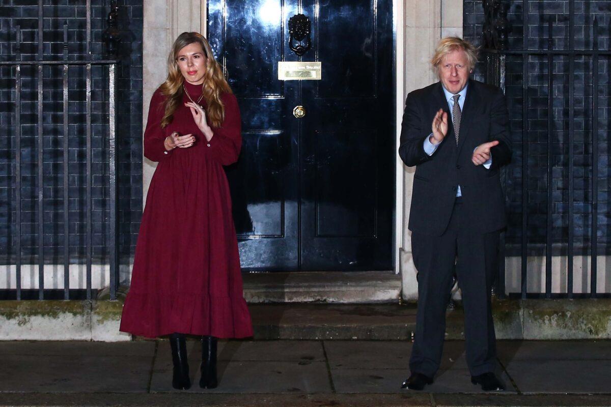 UK Prime Minister Boris Johnson and his fiancee Carrie Symonds take part in a doorstep clap in memory of Captain Sir Tom Moore outside 10 Downing Street on Feb. 3, 2021. (Hollie Adams/Getty Images)