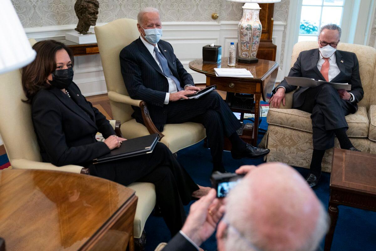 Sen. Patrick Leahy (D-Vt.) takes a photo of (L–R) Vice President Kamala Harris, President Joe Biden, and Senate Majority Leader Chuck Schumer (D-N.Y.) during a meeting to discuss a CCP virus relief package, in the Oval Office of the White House on Feb. 3, 2021. (Evan Vucci/AP Photo)