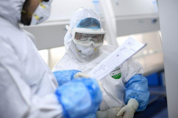 Laboratory technicians speak while working on samples to be tested for COVID-19 at a BGI laboratory in Wuhan, China, on Feb. 6, 2020. (STR/AFP via Getty Images)