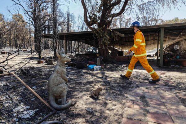 A man in a fire suit walks past an ornamental statue of a kangaroo in the yard of a razed house after bushfires in Gidgegannup, some 40 kilometres north-east of Perth on Feb. 4, 2021. (Trevor Collens/AFP)